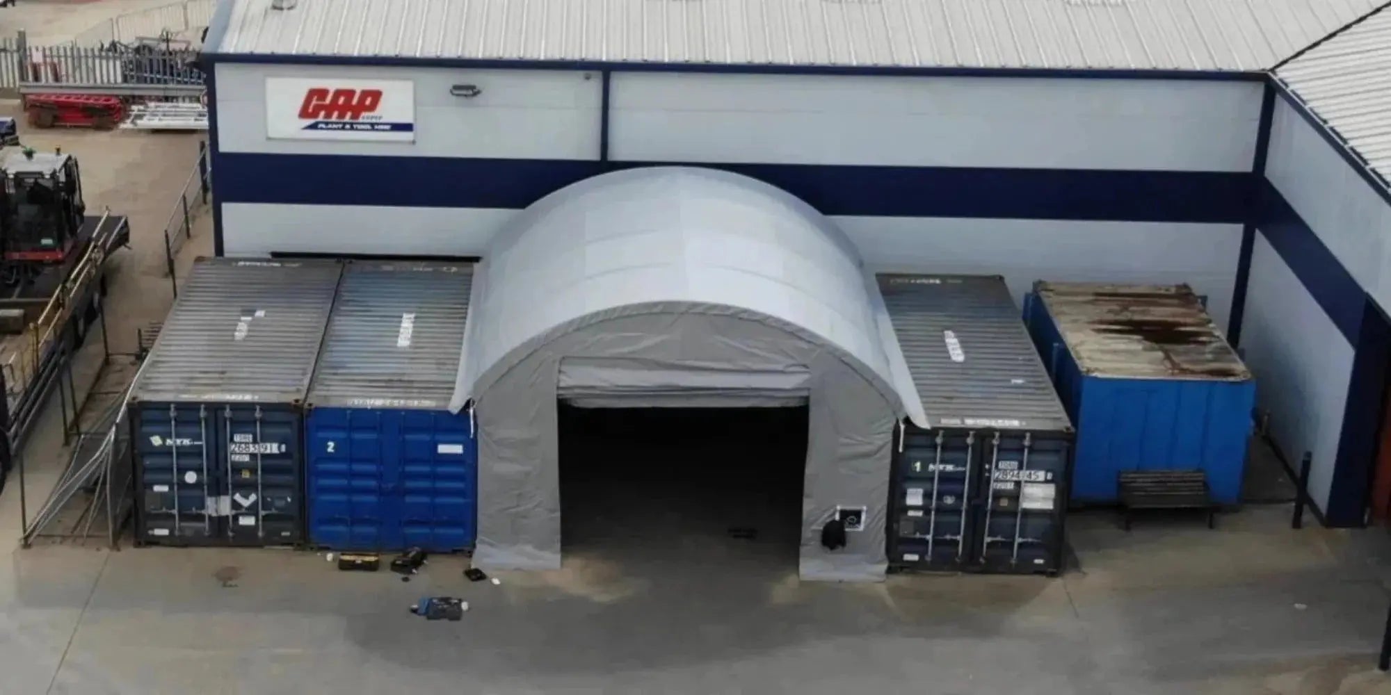 Exterior view of a grey-white domed shelter attached to dark blue shipping containers.